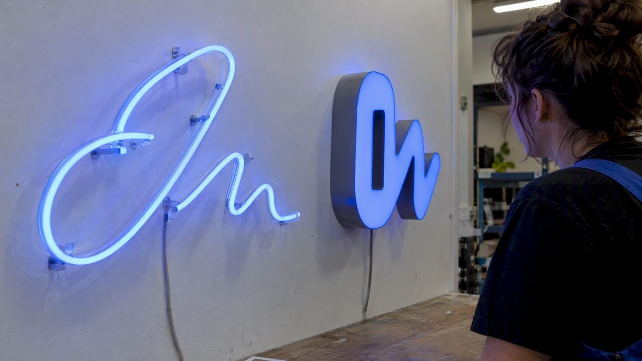 Exposed script tubing beside bold face-mounted sign